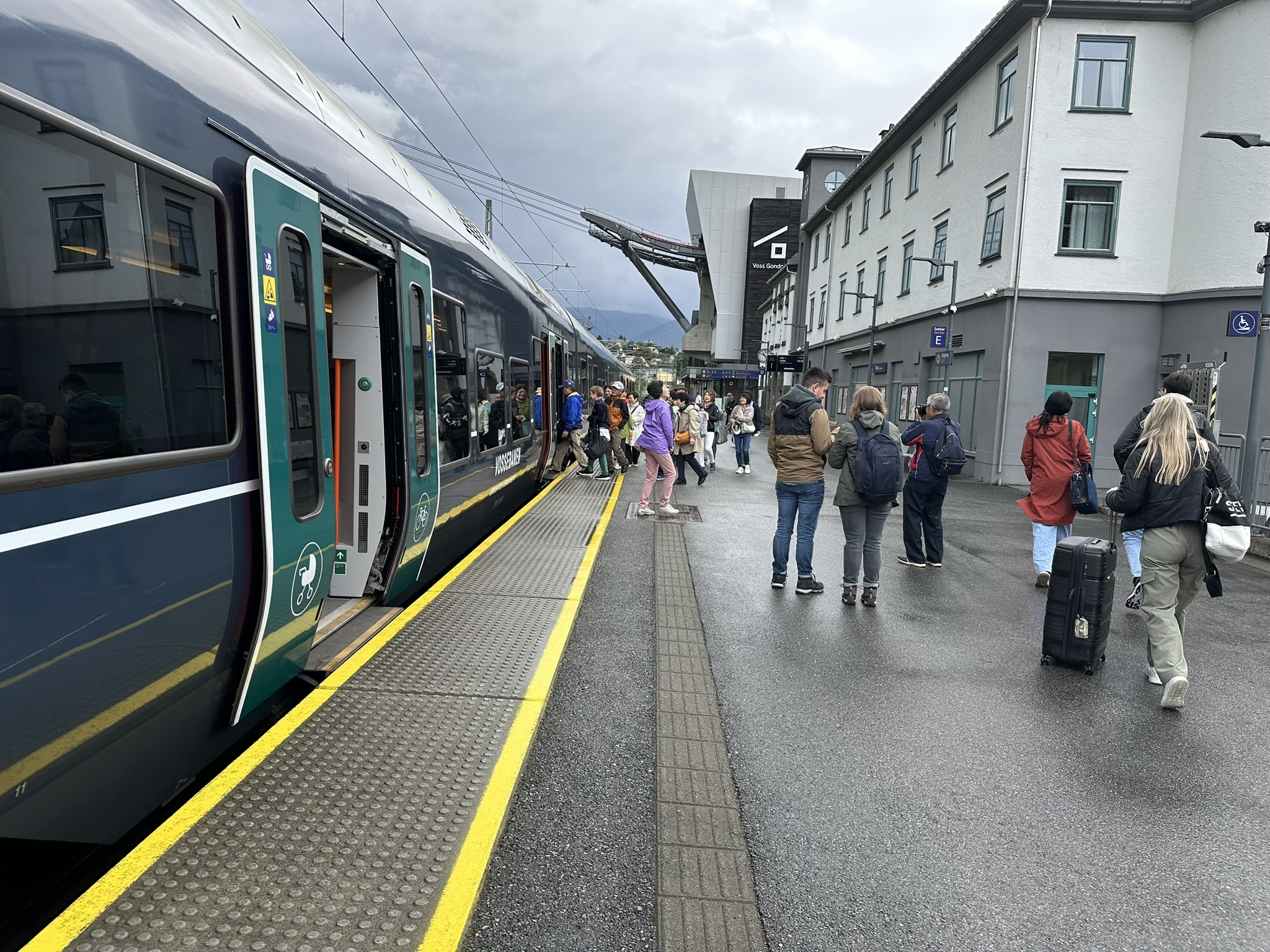 Voss stasjon. Turister og hverdagsreisende i skjønn forening.