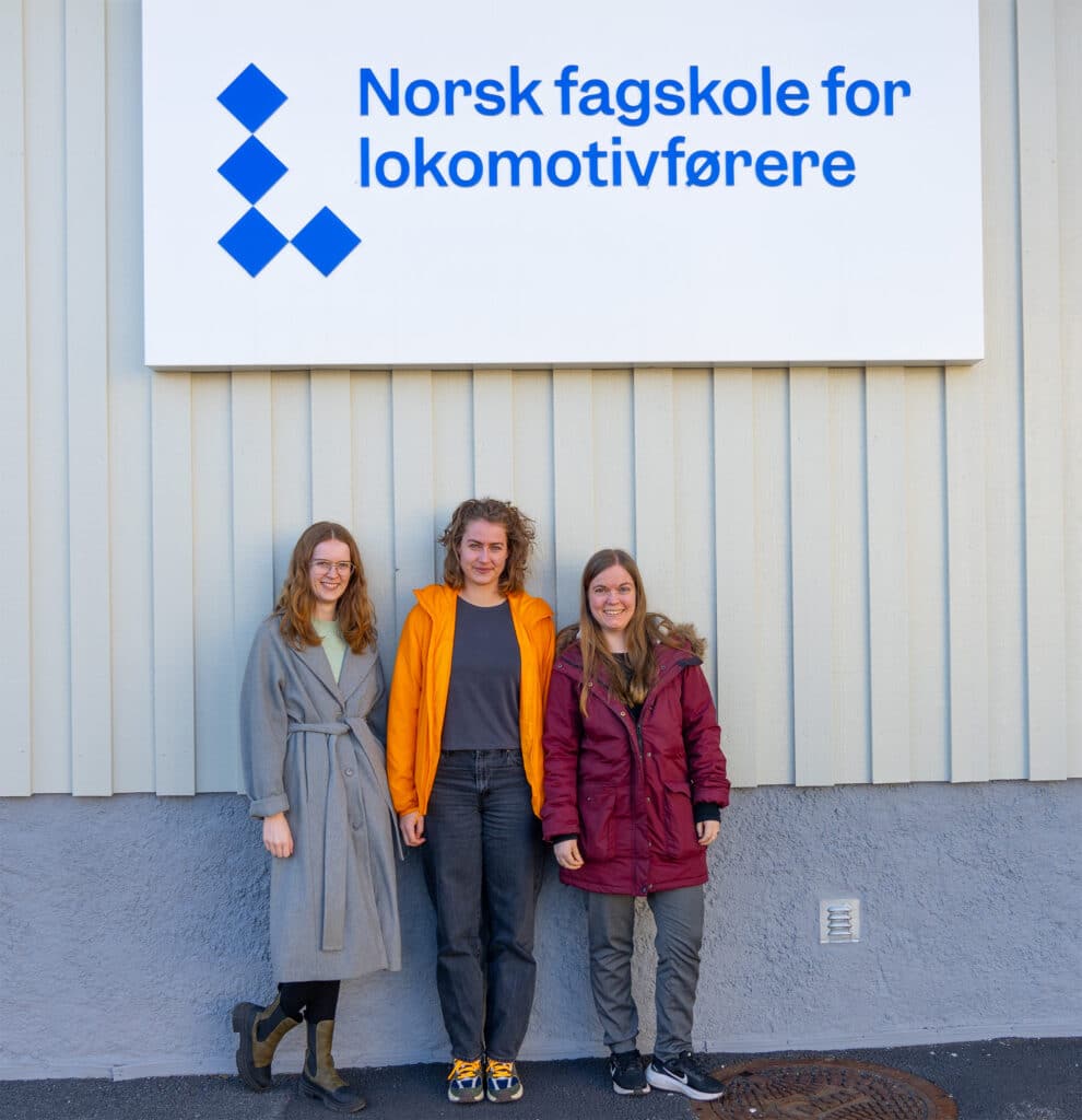 Kvinnelige studenter under skiltet til Norsk fagskole for lokomotivførere